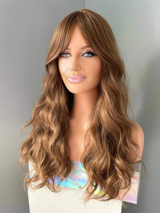Long brown curly wig with fringe displayed on a mannequin, featuring soft flowing curls and modern fringe.