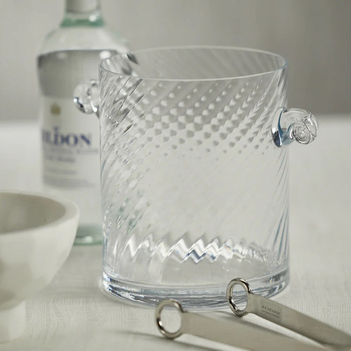 The ZODAX BAGATELLE SWIRL ICE BUCKET features clear glass with a subtle diagonal swirl pattern, two small side handles, and measures 6 in x 7 in (15.24 cm x 17.78 cm), displayed on a white background.
