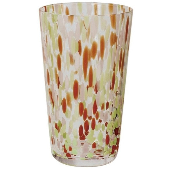 A selection of CREATIVE COOP HAND-BLOWN CONFETTI DRINKING GLASS tumblers, each with red, yellow, and pastel speckles, is displayed on a light surface; a tall glass holds drink stirrers and a cocktail recipe card.