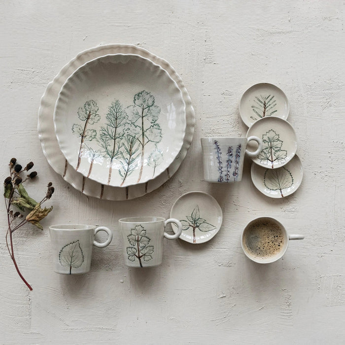 Four white HAND-PAINTED STONEWARE MUGS WITH BOTANICAL DESIGN from CREATIVE COOP are lined up side by side, each featuring unique flower and leaf illustrations and a comfortable round handle to brighten your morning routine.