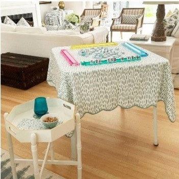 The HOLLY STUART DESIGNS Mahjong and Game Tablecloth in Dash Green Tea features a folded white cotton cloth with a green brushstroke pattern, tied with a white ribbon—perfect for elevating any game or mahjong table.