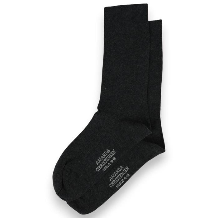 A pair of anthracite melange mid-calf socks from AMANDA CHRISTENSEN, crafted in a luxurious cotton and cashmere blend with white text on the soles, arranged on a white background—these NOBLE socks showcase timeless style and meticulous attention to detail.