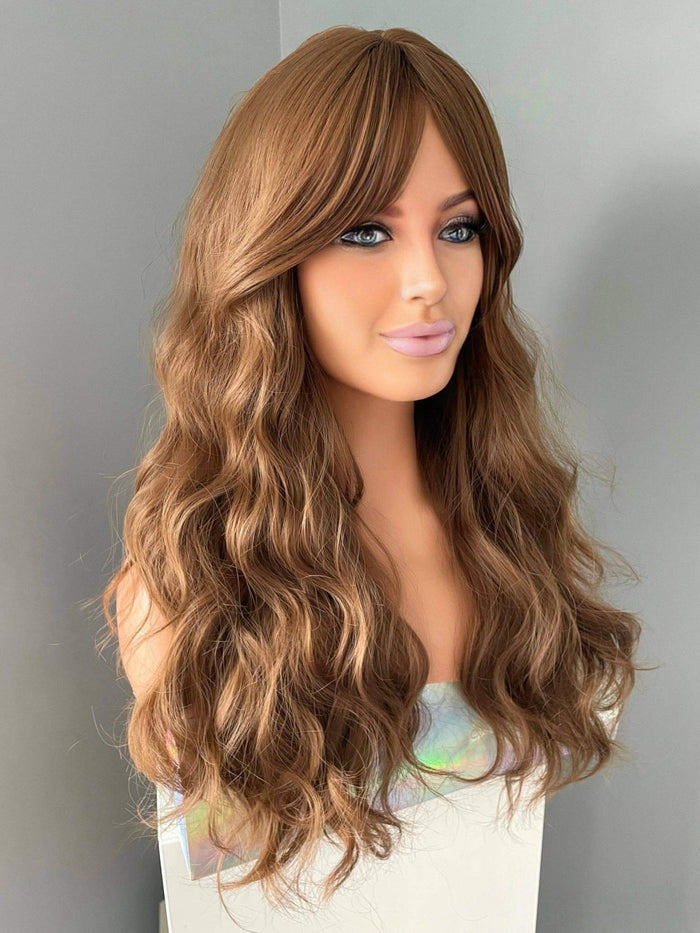long brown curly wig with fringe displayed on a mannequin, featuring soft curls and curtain bangs.