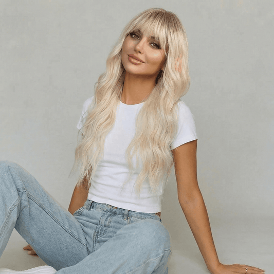 Blaire Ash Blonde Beach Wave Synthetic Wig with Bangs worn by a model with long waves and full fringe.