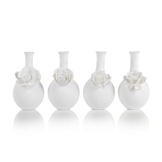 The CAMEO LONG NECK PORCELAIN BUD VASE by ZODAX is a round, white vase with a matte finish, featuring a narrow neck and a detailed floral embellishment on the front.