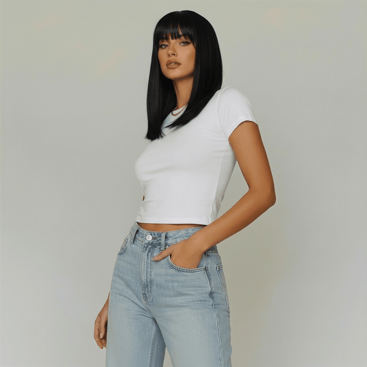 Model showcasing the Cecil short black wig with bangs, wearing a white cropped shirt and light blue jeans.