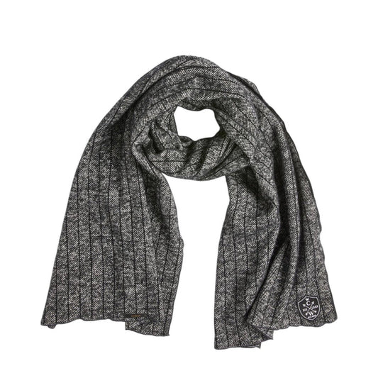 The CLIFTON WILSON - BLACK PINSTRIPE HERRINGBONE WOOL SCARF by CLIFTON WILSON, featuring a black pinstripe herringbone pattern in wool and a small embroidered patch at one end, is displayed flat against a white background.