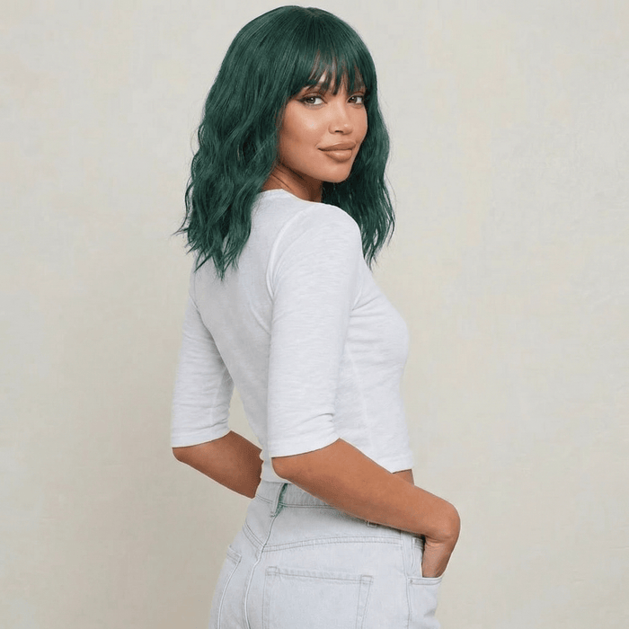 Short green wig with bangs displayed on a model, featuring wavy texture and bold emerald color.