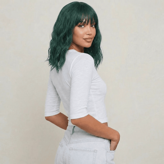 Short green wig with bangs displayed on a model, featuring wavy texture and bold emerald color.