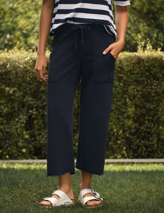 A person stands outdoors with one hand casually placed in their pocket, wearing the FRANK & EILEEN Penny Patch Pocket Jersey Pant in British Royal Navy.