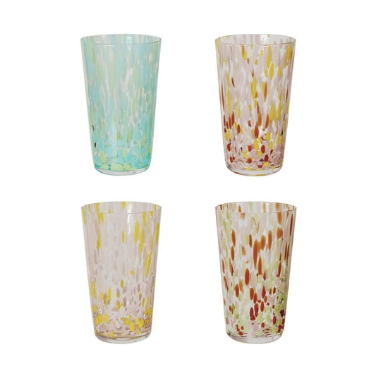 A selection of CREATIVE COOP HAND-BLOWN CONFETTI DRINKING GLASS tumblers, each with red, yellow, and pastel speckles, is displayed on a light surface; a tall glass holds drink stirrers and a cocktail recipe card.