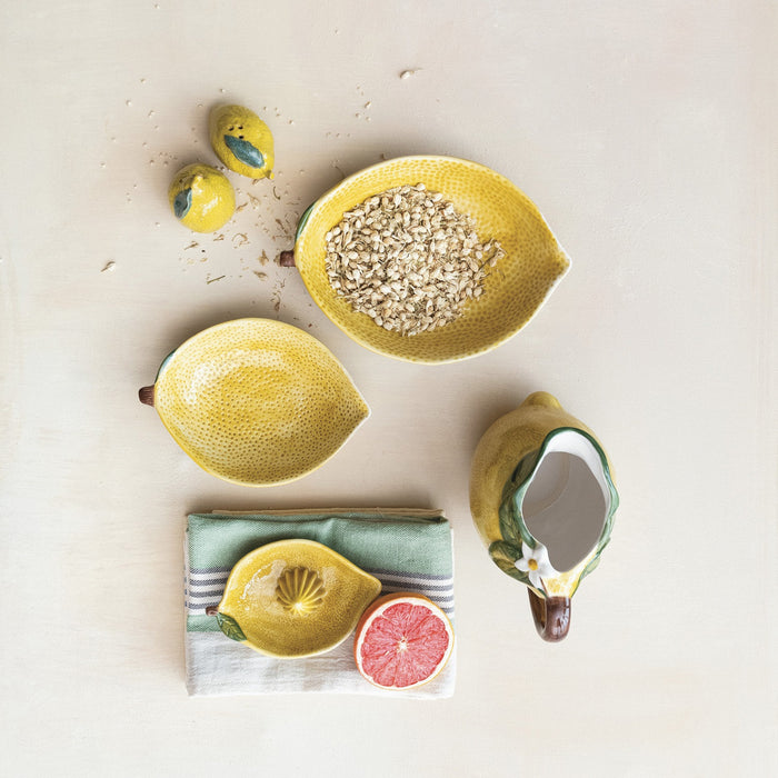 The CREATIVE COOP HAND-PAINTED STONEWARE LEMON SHAPED BOWL, LARGE features a textured yellow finish with a green leaf accent, making it a perfect decorative citrus bowl.