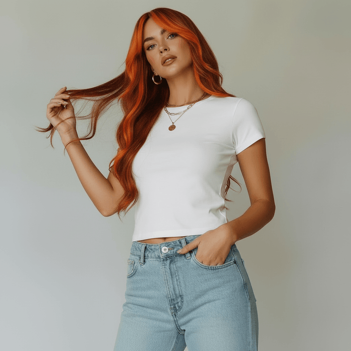Model showcasing a black wig with orange highlights, wearing a white cropped top and light jeans, posing confidently.