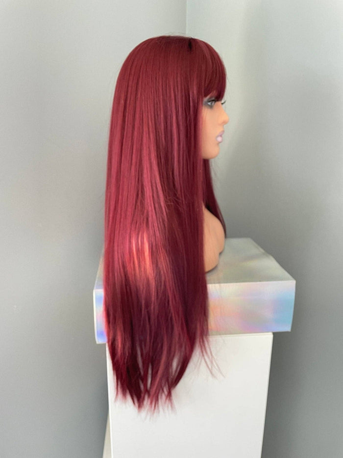 Red wig on a mannequin head against a plain background