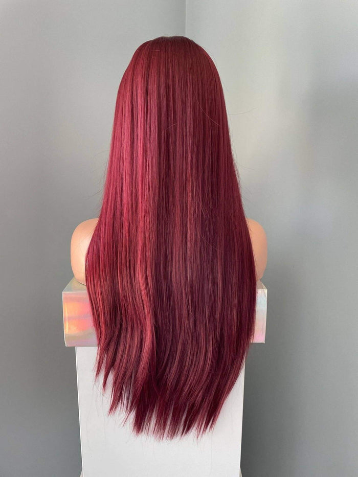Red wig on a mannequin head against a neutral background