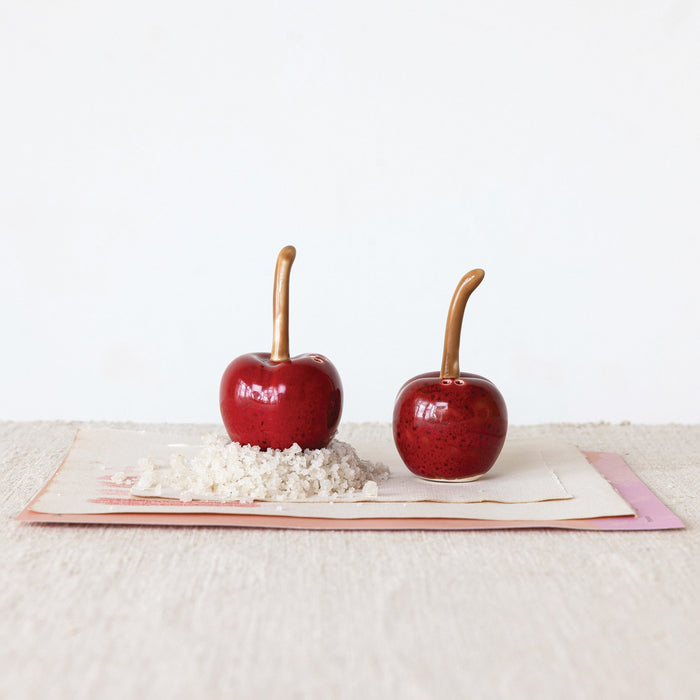Add a charming touch to your kitchen with CREATIVE COOP’s STONEWARE CHERRY SHAPED SALT AND PEPPER SHAKERS—dark red ceramic cherries with brown stems, perfect for vintage decor.